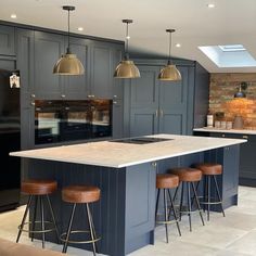 a kitchen island with stools in front of it and three lights hanging from the ceiling