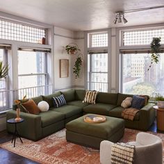 a living room filled with lots of furniture next to large windows and potted plants