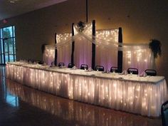 a long table covered in white cloths and lights