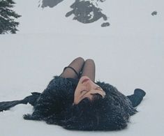 a woman is laying in the snow with her head on her back and eyes closed