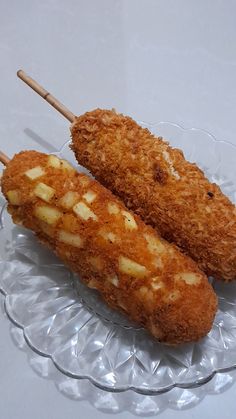 two pieces of fried food on a glass plate with toothpicks sticking out of it