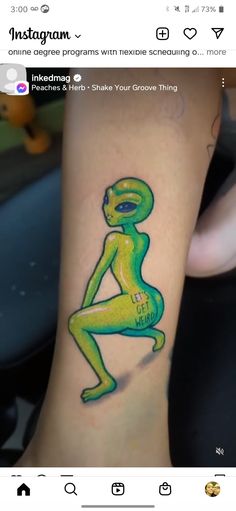 an alien tattoo on the leg of a person's leg, with text underneath it