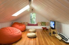 an attic bedroom with two bean bags on the floor and a television in the corner