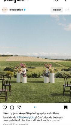 two tall vases with flowers are sitting in the grass near some chairs and tables