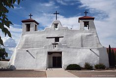 an old white church with three crosses on the roof