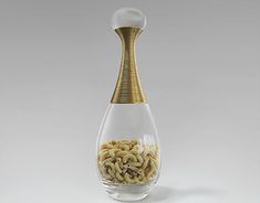 a glass vase filled with lots of pasta in it's bottom and gold trimmings