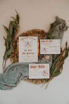 the wedding stationery is laid out on a wicker basket with leaves and ribbons