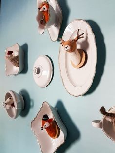 there are several deer figurines sitting on the plates with cups and saucers