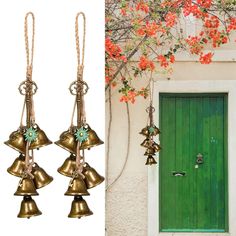 three bells hanging from the side of a building next to a green door with red flowers on it