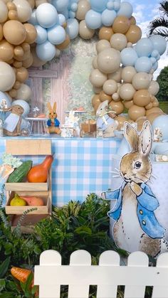 a table topped with lots of balloons next to a wall covered in animals and rabbits