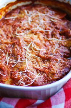 a casserole dish with meat and cheese in it on a red and white checkered table cloth