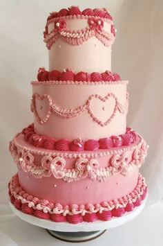 a three tiered cake with pink icing and hearts