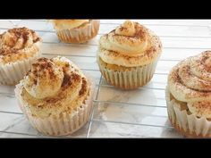 cupcakes with cinnamon on top sitting on a cooling rack in front of other cupcakes