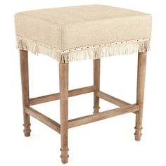 an upholstered stool with fringe trimmings on the legs and foot rest