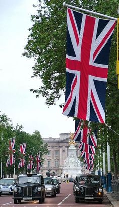 the british flag is flying high in the air above cars parked on the side of the road