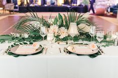 the table is set with flowers and greenery for an elegant wedding reception or special event