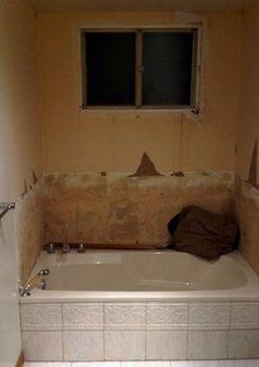 an unfinished bathroom with a bathtub and window in the wall, next to a tiled floor