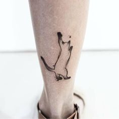 a small cat tattoo on the ankle is shown in black and grey ink, with an outline