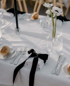 the table is set with silverware and white flowers