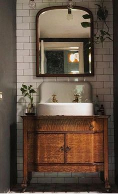 a bathroom sink sitting under a mirror on top of a wooden cabinet next to a doorway