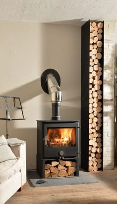 a wood burning stove in a living room next to a pile of firewood on the floor