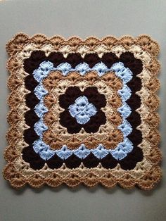 a crocheted square with blue and brown squares on it's sides, sitting on a gray surface