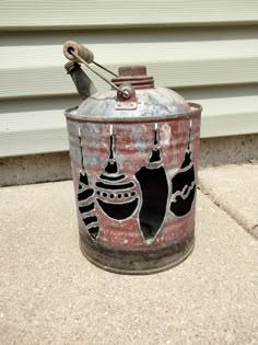 an old tin can with ornaments painted on it sitting in front of a garage door