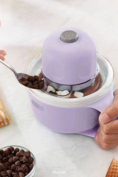 a person scooping ice cream out of a purple blender with chocolate chips and marshmallows