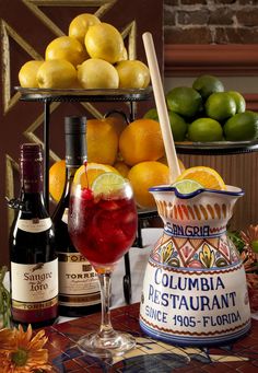 there are many different types of drinks on the table with lemons and limes in the background