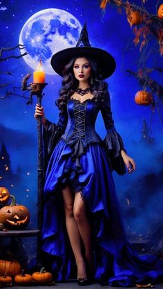 a woman dressed as a witch holding a candle in front of a backdrop with pumpkins