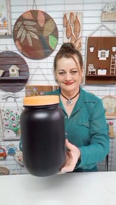 a woman holding a large black jar in her hands