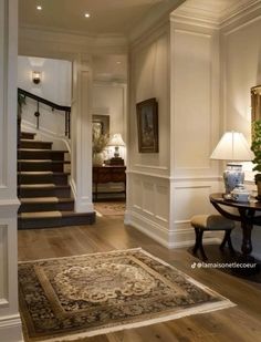 an entry way with stairs and rugs on the floor in front of a table