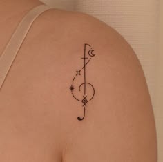 a tattoo on the back of a woman's left shoulder, which has a musical note and stars