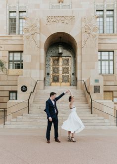 a man and woman dancing in front of a large building with steps leading up to it