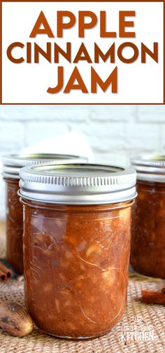 three jars filled with cinnamon jam sitting on top of a table next to an apple