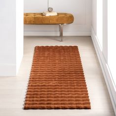 an orange rug in the middle of a room with a bench and window behind it