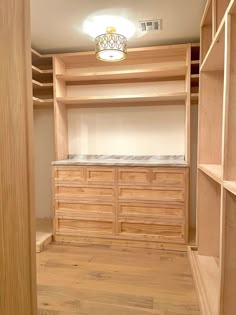 an empty walk in closet with wooden shelves and drawers