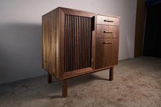 a wooden cabinet sitting on top of a carpeted floor next to a white wall