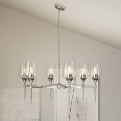 a chandelier with wine glasses hanging from it's arms in a room