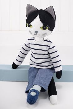 a black and white cat stuffed animal sitting on top of a blue shelf next to a wall