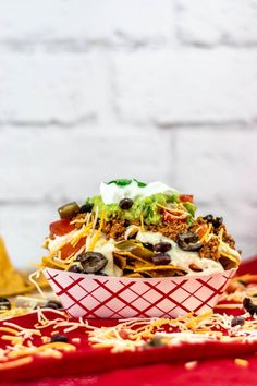 a bowl filled with taco salad sitting on top of a red cloth covered table