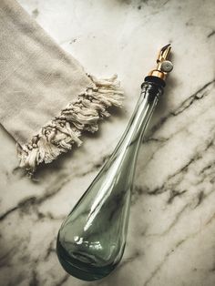 an empty glass bottle sitting on top of a marble counter next to a towel and cloth