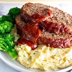 meatloaf, mashed potatoes and broccoli on a plate with sauce