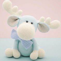 a crocheted blue and white elephant sitting on top of a table next to a pink wall