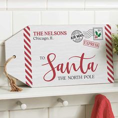 a sign that says santa the north pole on a shelf next to a potted plant