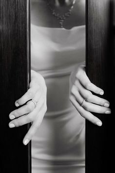 a black and white photo of a woman with her hands on the door