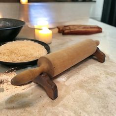 a wooden rolling pin sitting on top of a counter next to some plates with food