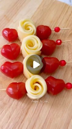 some food that is on top of a wooden table with toothpicks in the shape of hearts