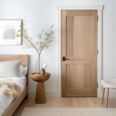 a bedroom with a wooden door and white walls