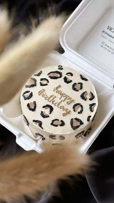 a birthday cake with leopard print on it sitting in a white box next to some fur